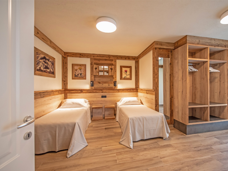 Chambre confortable avec lits simples, mobilier en bois et éclairage doux.