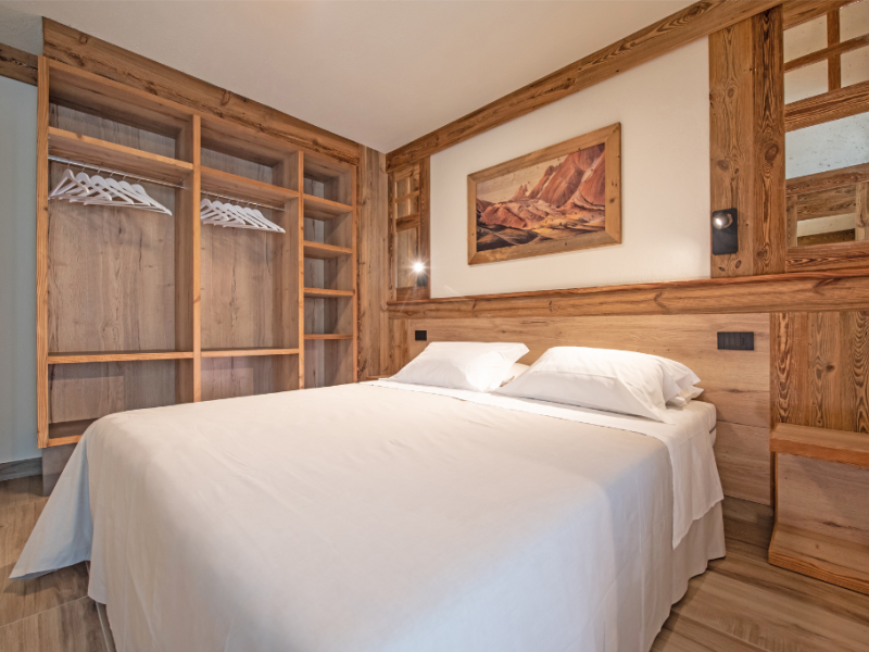 Rustic bedroom with double bed and open wardrobe.