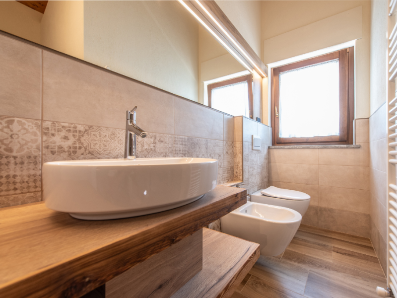 Salle de bain moderne avec lavabo, bidet et fenêtre lumineuse.