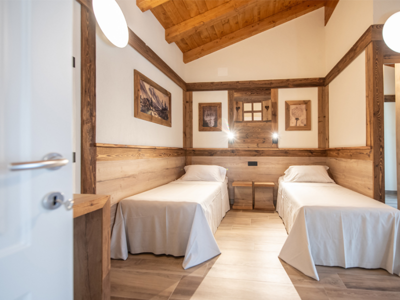 Gemütliches Zimmer mit zwei Einzelbetten und Holzdekorationen.